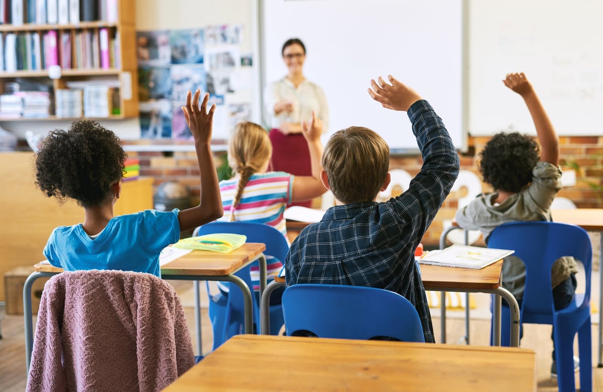 White nursery school children with teacher sitting on floor indoors in classroom having lesson