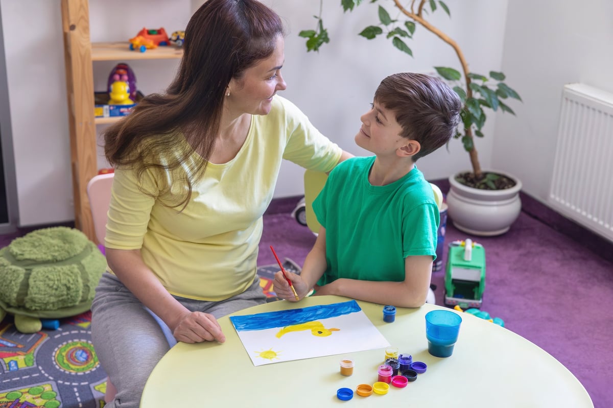 White boy playing with colorful wooden activity cube for sensory play and cognitive development