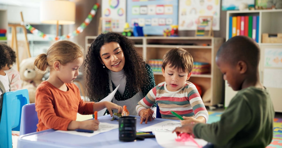 Teacher helping white children drawing and learning in classroom, creative art education