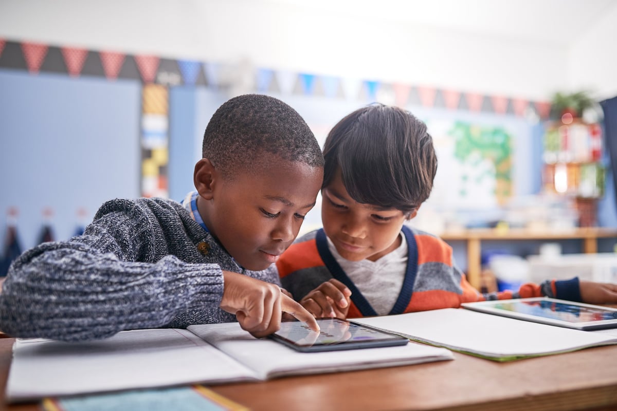 White elementary school children using a tablet in class